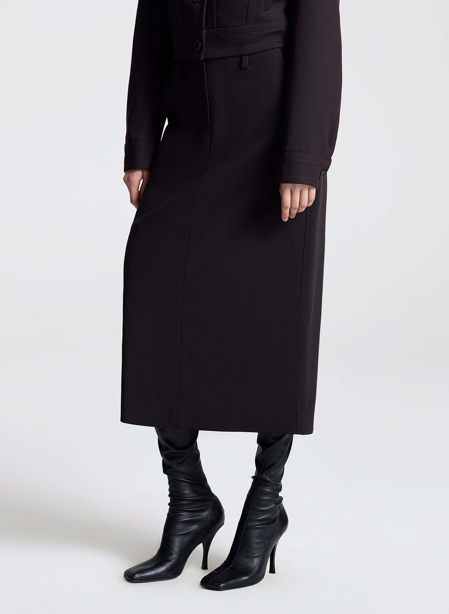 woman wearing a dark brown jacket and matching skirt