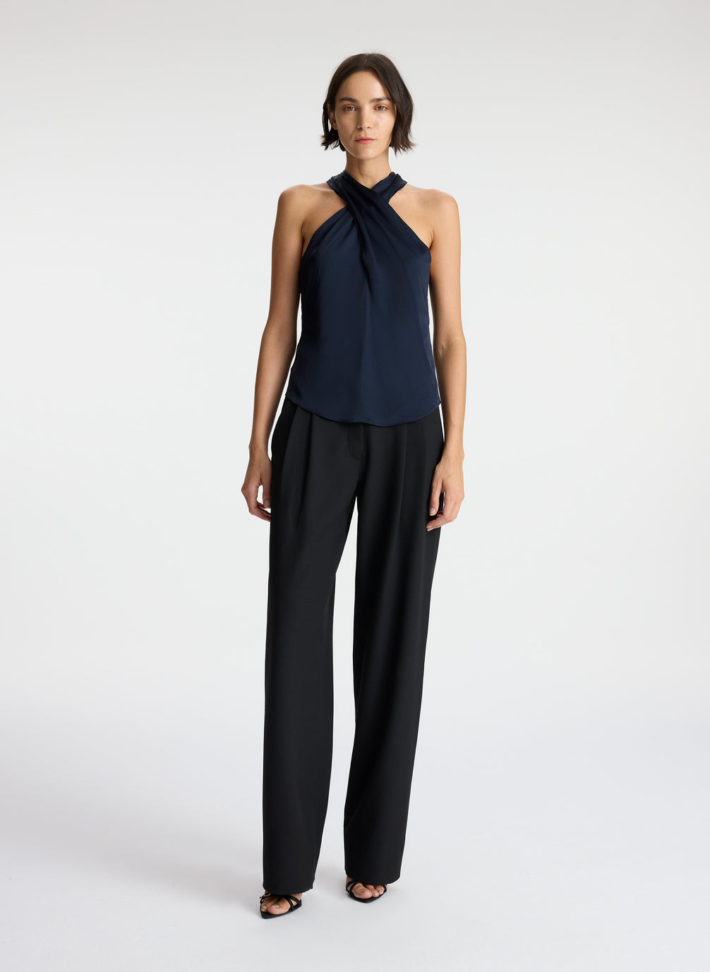 front view of woman wearing navy blue satin halter top with black pants
