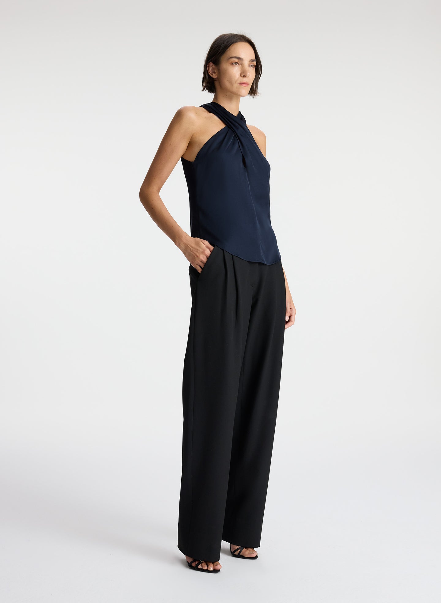 side view of woman wearing navy blue satin halter top with black pants