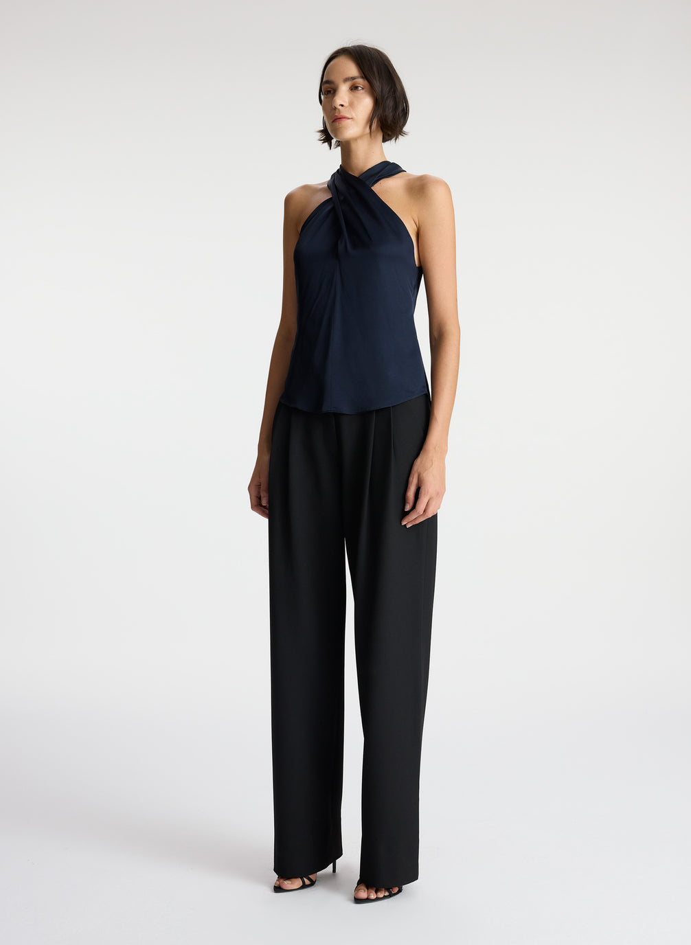 side view of woman wearing navy blue satin halter top with black pants