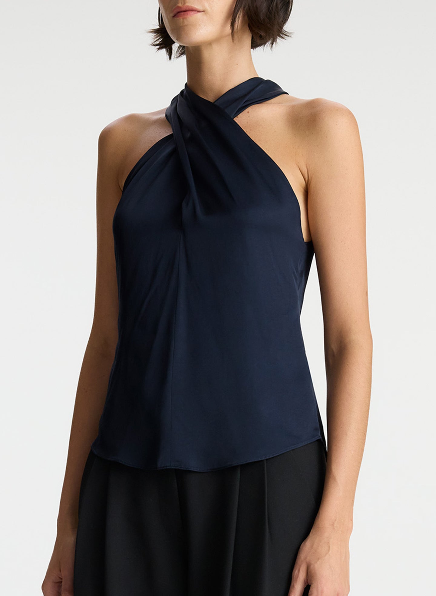 detail view of woman wearing navy blue satin halter top with black pants