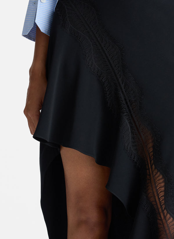 detail view of woman wearing blue striped button down collared shirt and asymmetric black satin and lace skirt