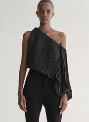 Woman wearing a black pleated one-shoulder top and black pants against a plain background