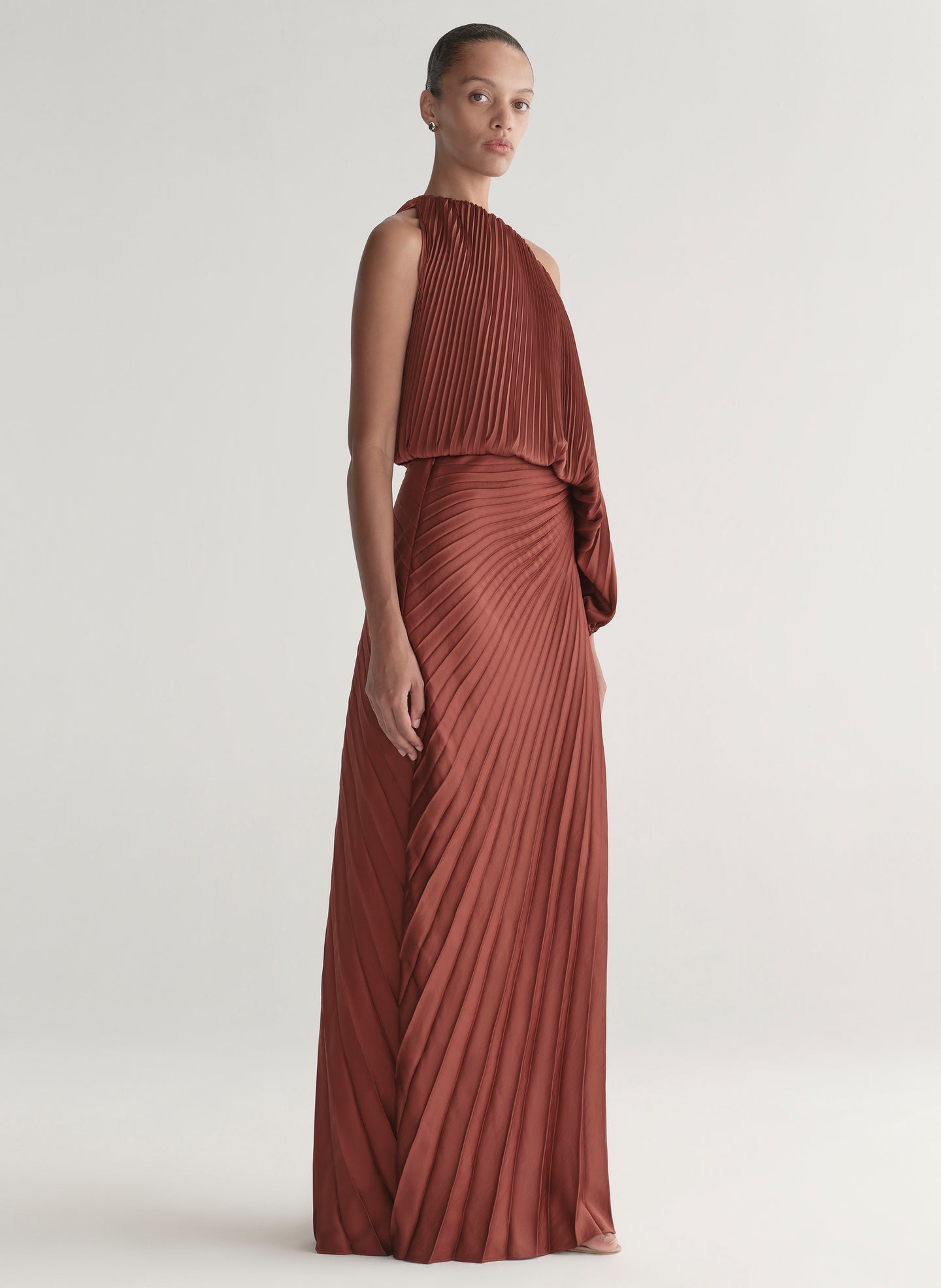 woman wearing maroon satin pleated one shoulder top and matching maxi skirt