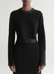 Woman wearing a black outfit with textured details on a plain background