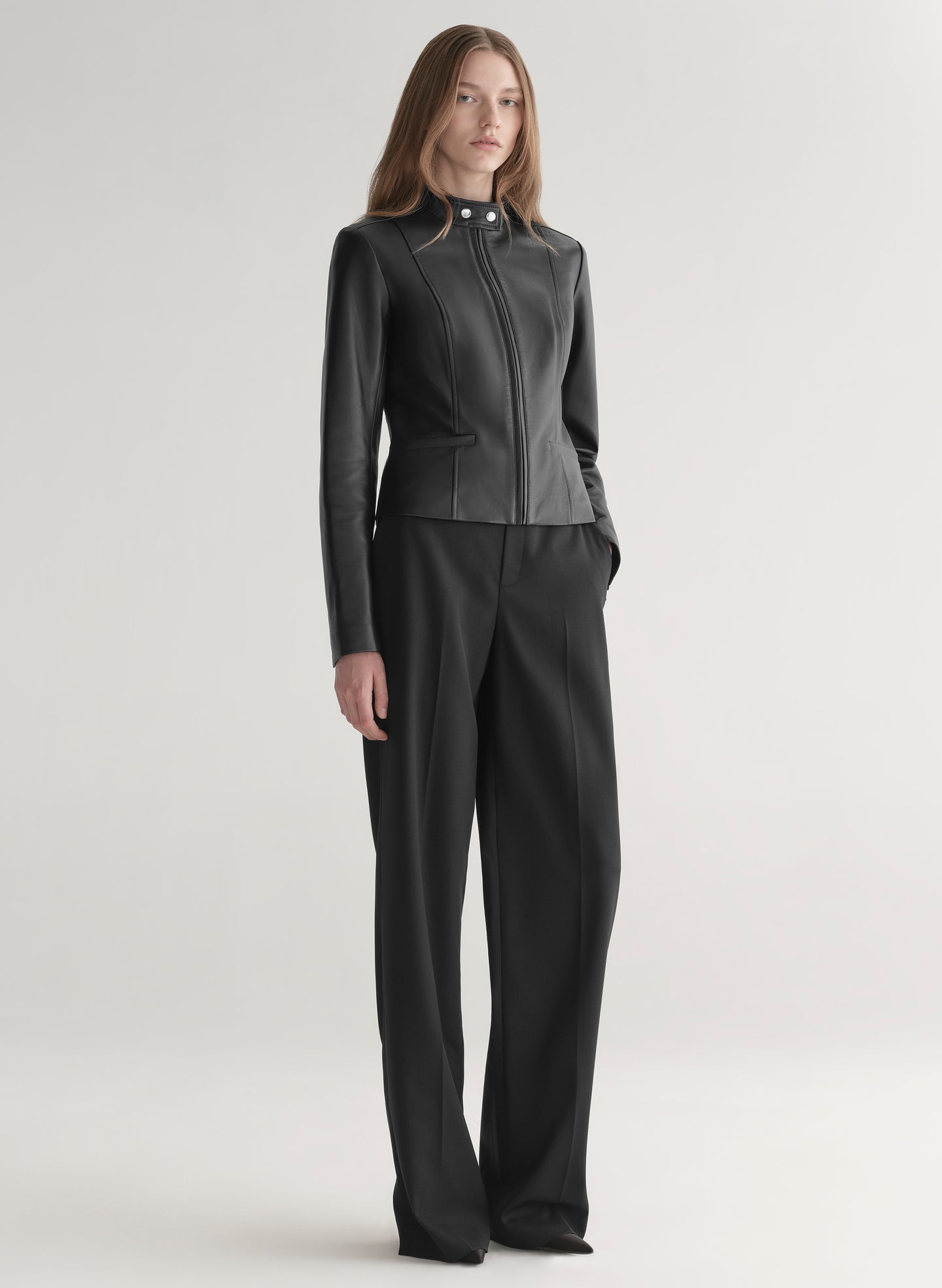 Person wearing a black leather jacket and pants on a white background