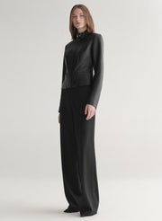 Person wearing a black outfit on a light gray background