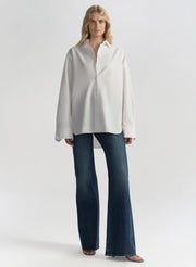 Woman wearing a white shirt and blue jeans on a plain background