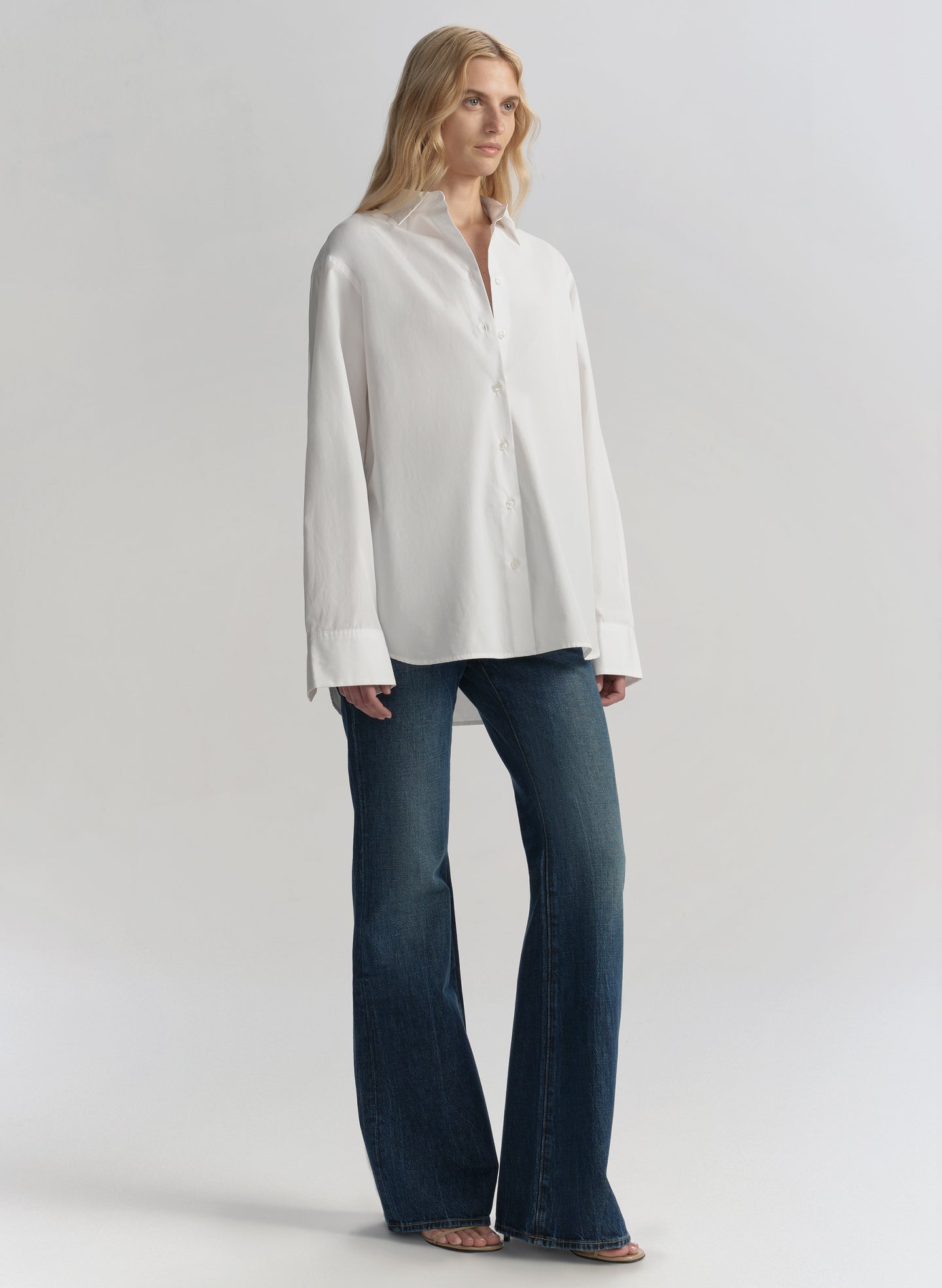 Woman wearing a white shirt and blue jeans on a plain background