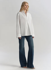 Woman wearing a white shirt and blue jeans on a plain background