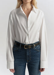 Woman wearing a white shirt and blue jeans on a plain background