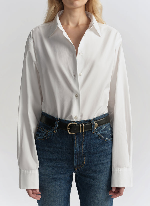 Woman wearing a white shirt and blue jeans on a plain background