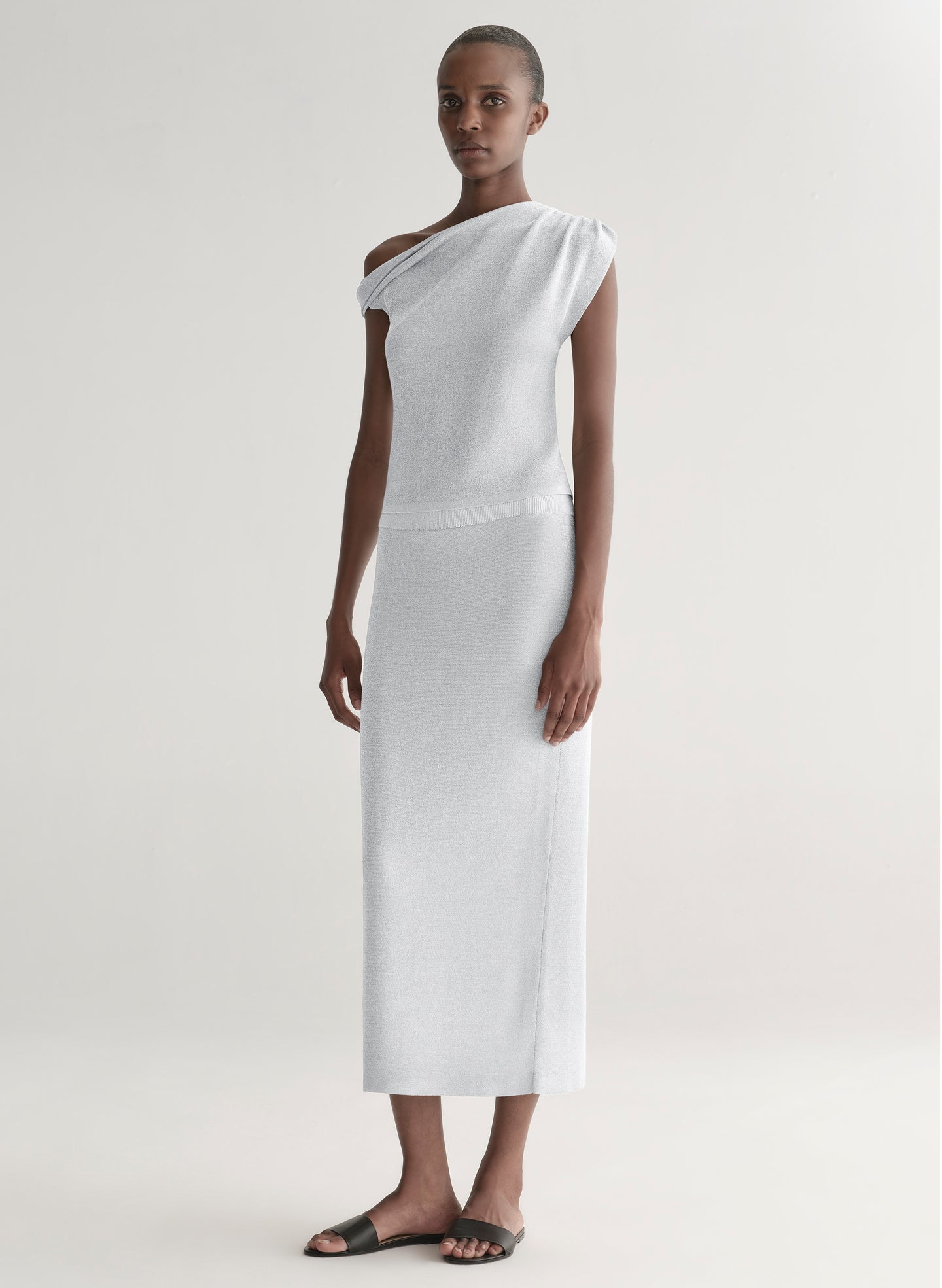 woman wearing silver knit top and matching midi skirt