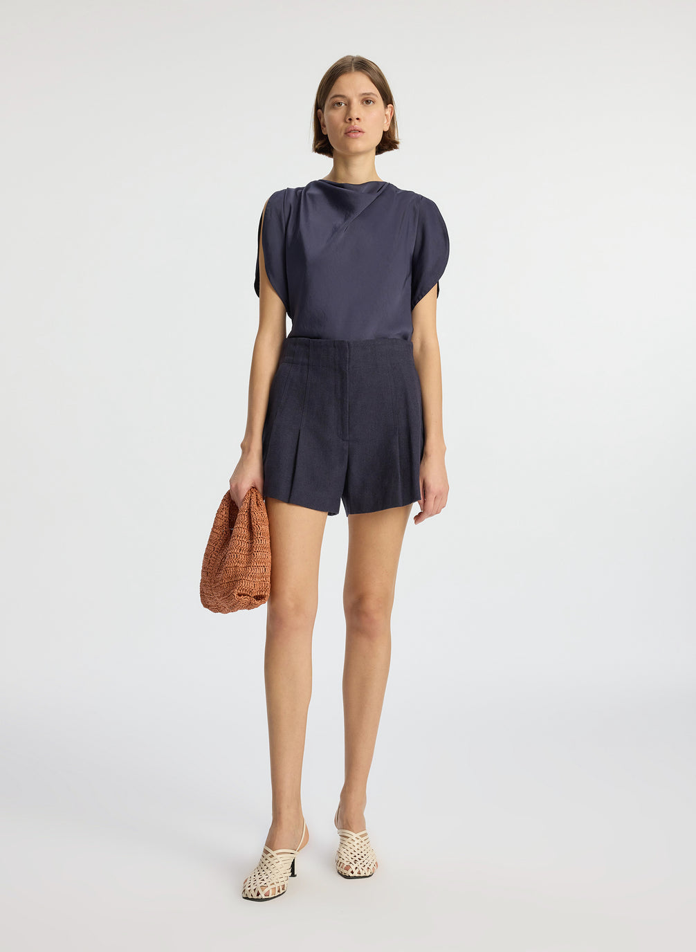 front view of woman wearing navy blue short sleeve satin blouse and navy blue shorts
