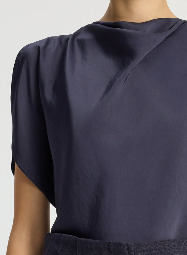detail view of woman wearing navy blue satin blouse and navy blue shorts