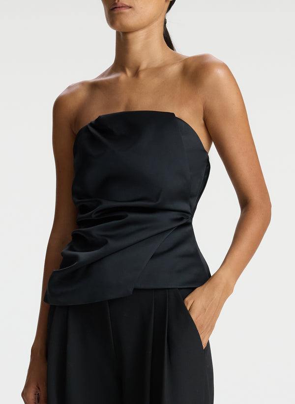 detail view of woman wearing black strapless satin top and black pants