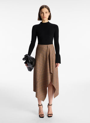 front view of woman wearing black sweater and brown plaid asymmetric midi skirt