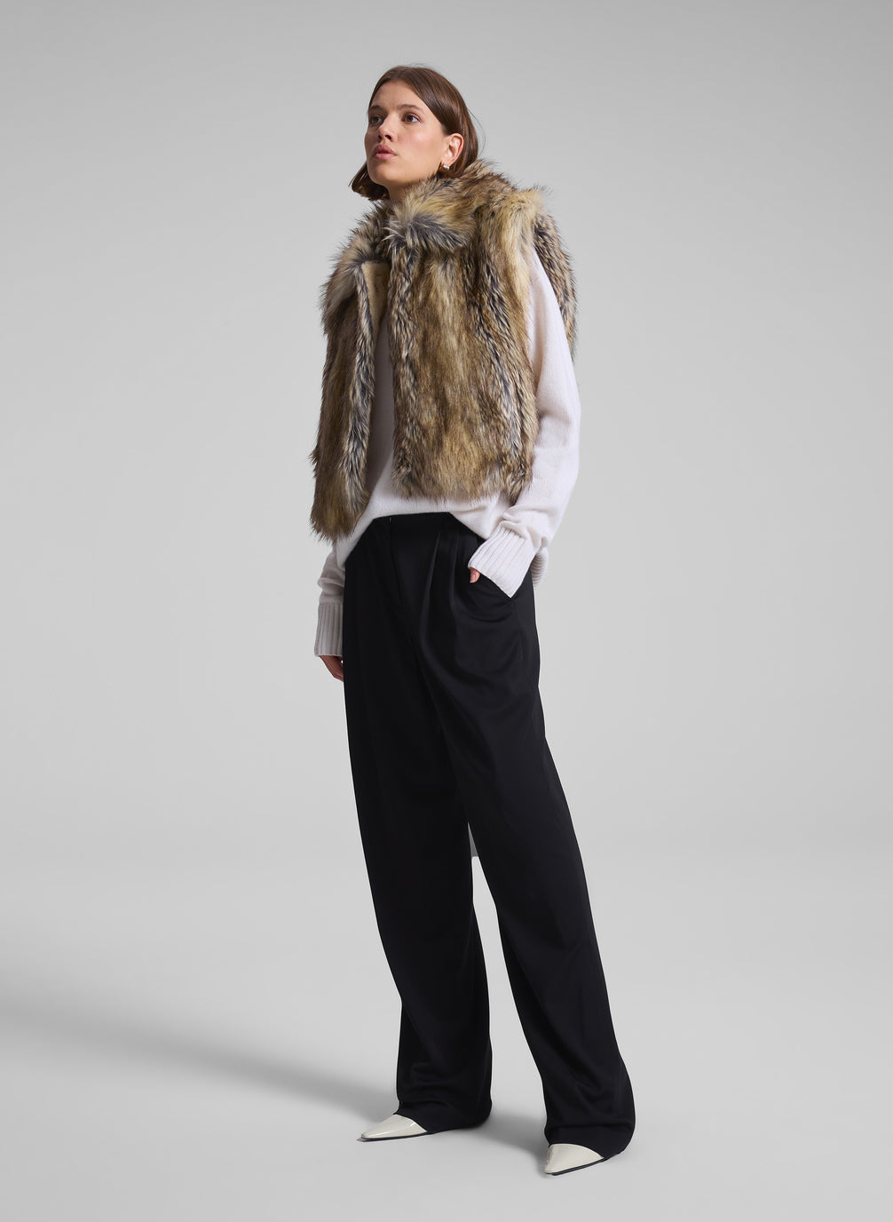 woman wearing brown faux fur vest, white sweater, and black pants