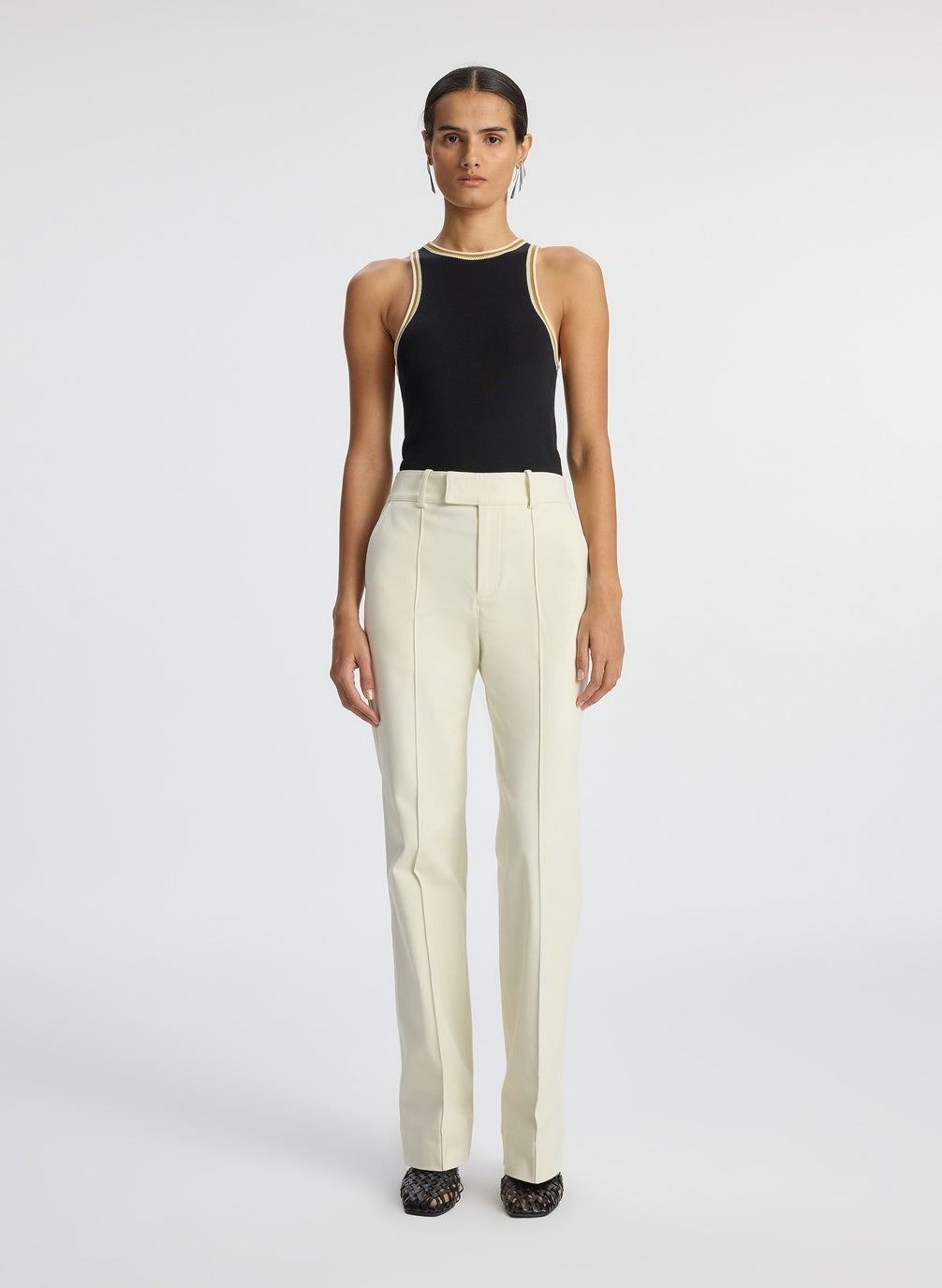 front view of woman wearing black tank top with contrast trim and cream pants