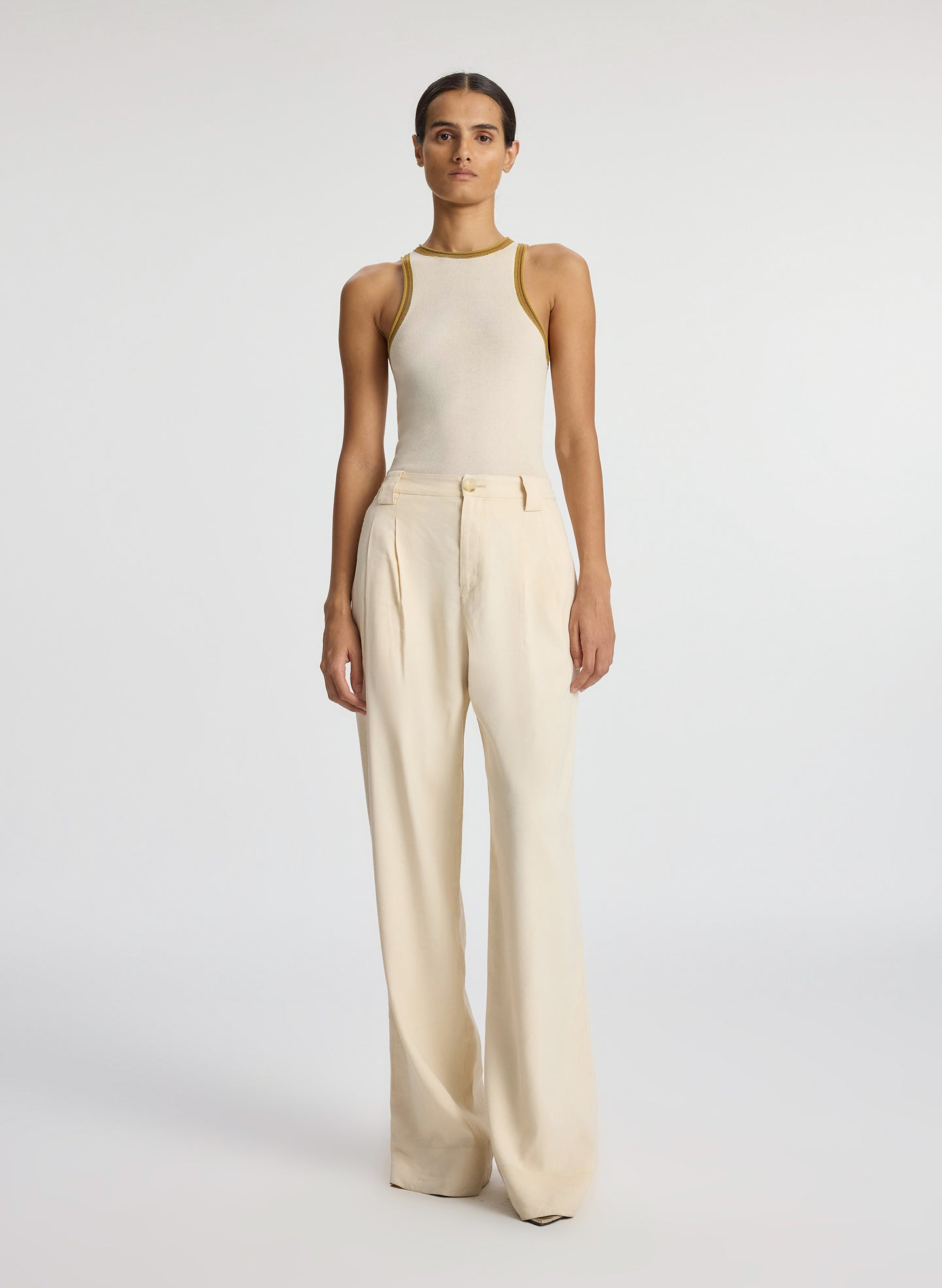Front view of woman wearing cream tank top and beige wide leg pants