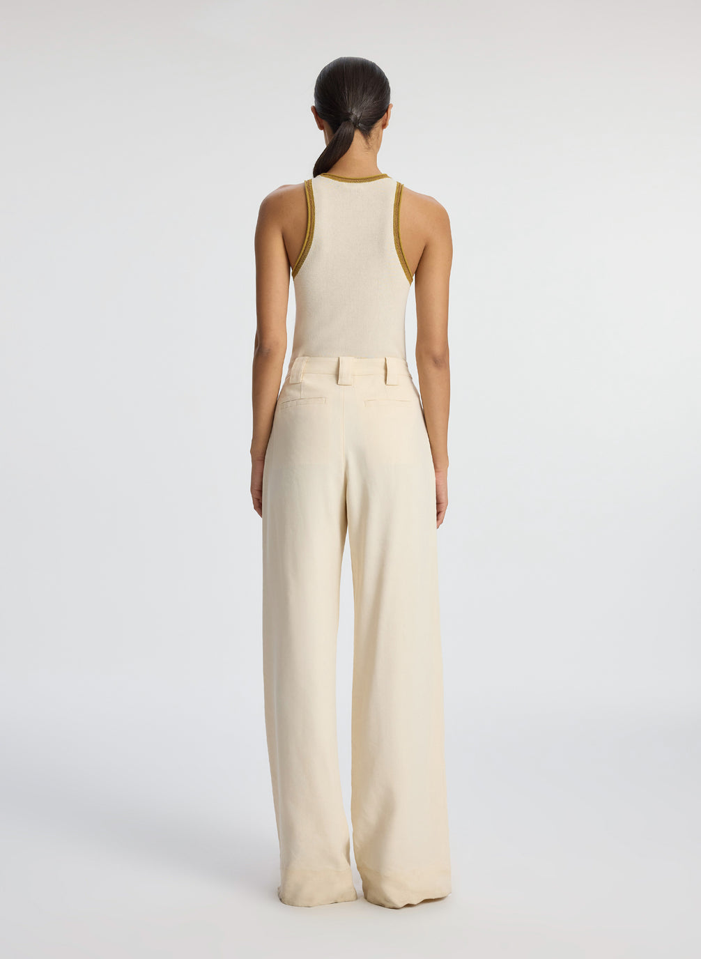 back view of woman wearing cream tank top and beige wide leg pants