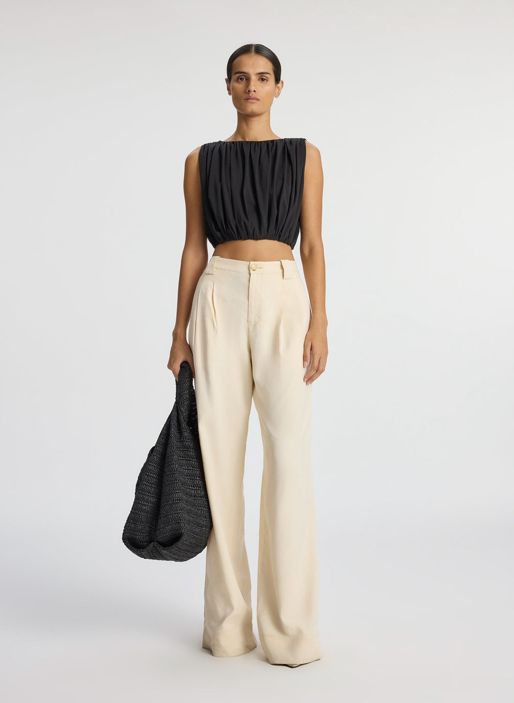 front view of woman wearing black sleeveless cropped top and beige wide leg pants