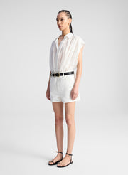 woman wearing white sleeveless top and white denim shorts