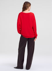 woman wearing red sweater and brown leather pants, not facing camera