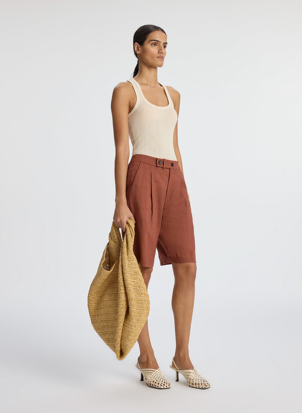 side view of woman wearing beige tank top and brown shorts