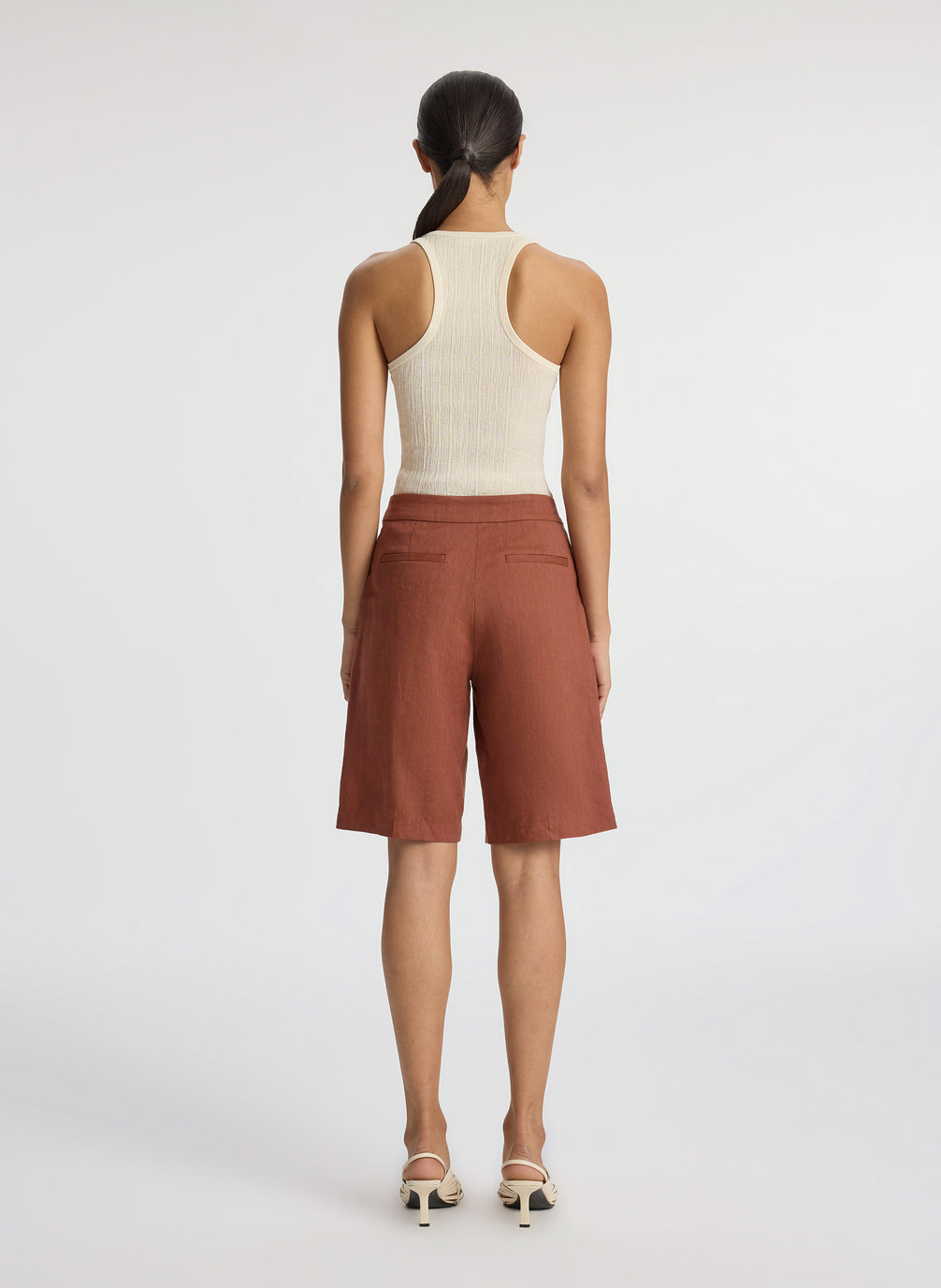 back view of woman wearing beige tank top and brown shorts