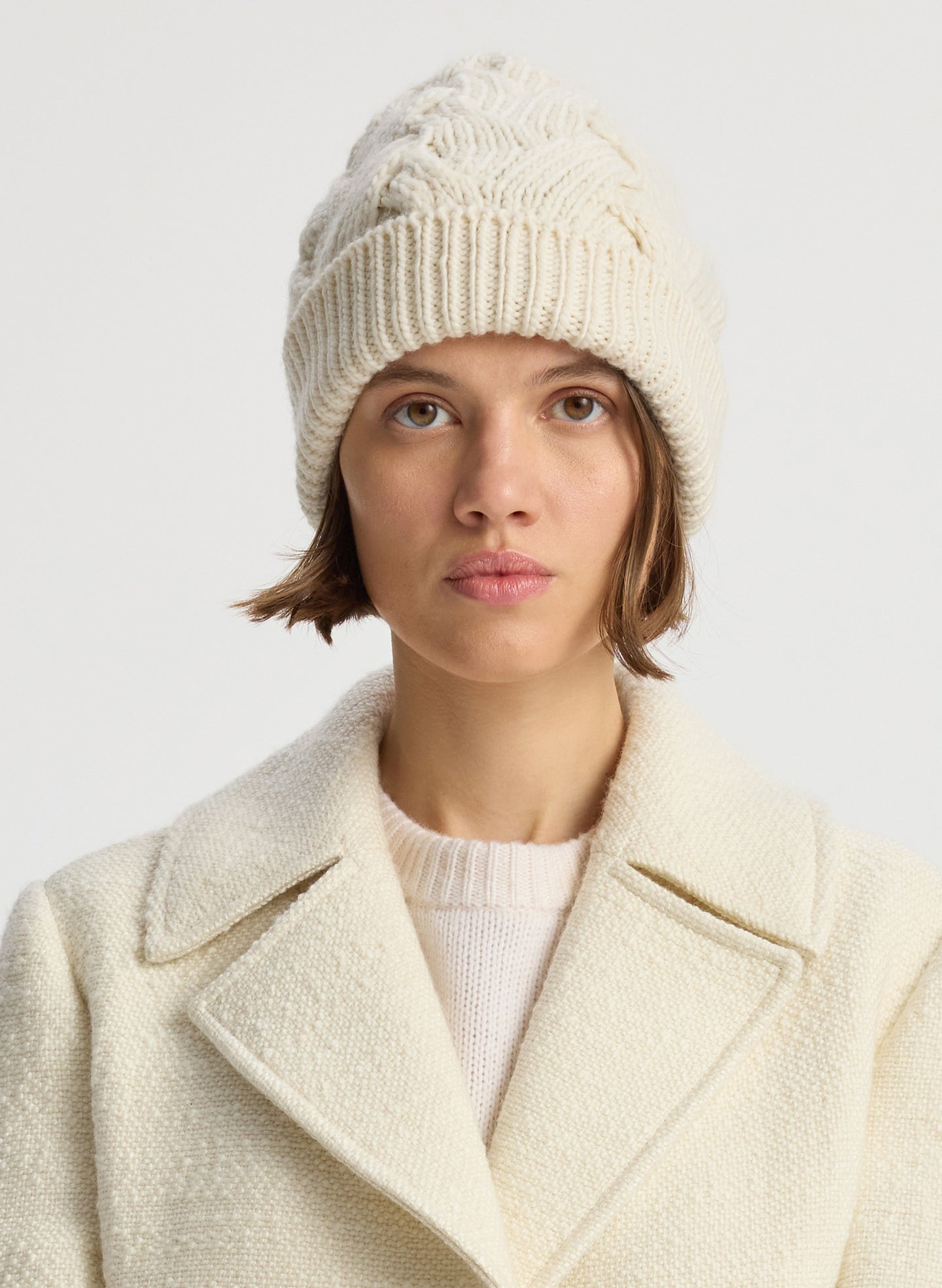 Front view of woman wearing cream cable knit beanie
