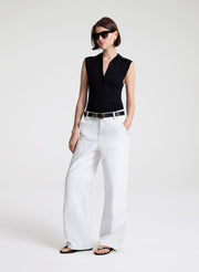 woman wearing  black sleeveless voile knit polo and white denim jeans