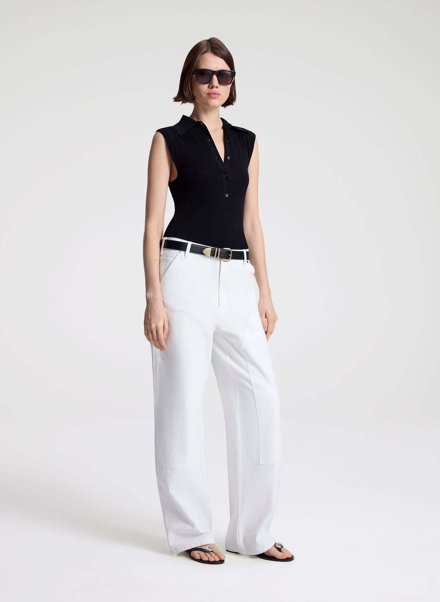 woman wearing  black sleeveless voile knit polo and white denim jeans