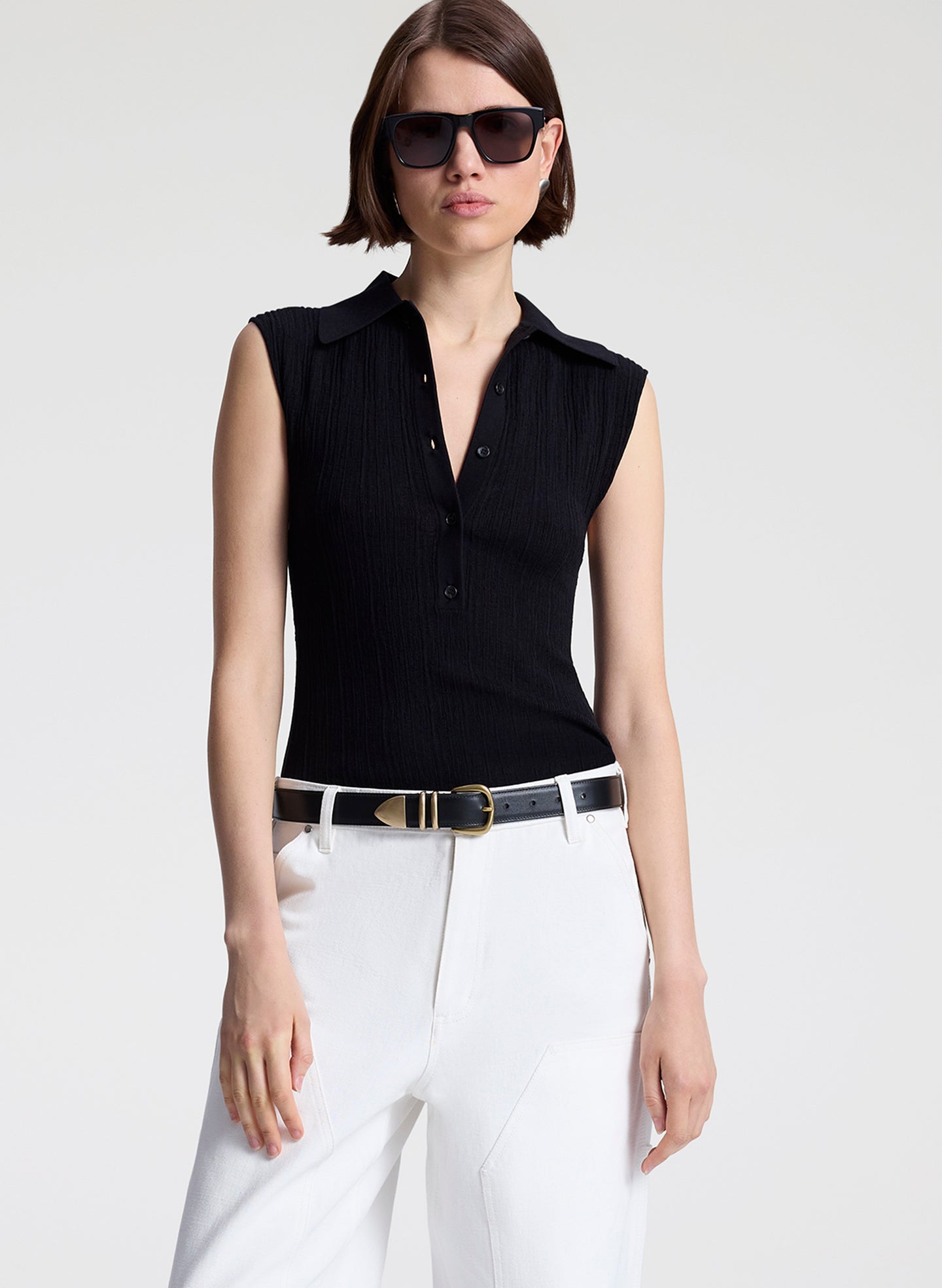 woman wearing  black sleeveless voile knit polo and white denim jeans