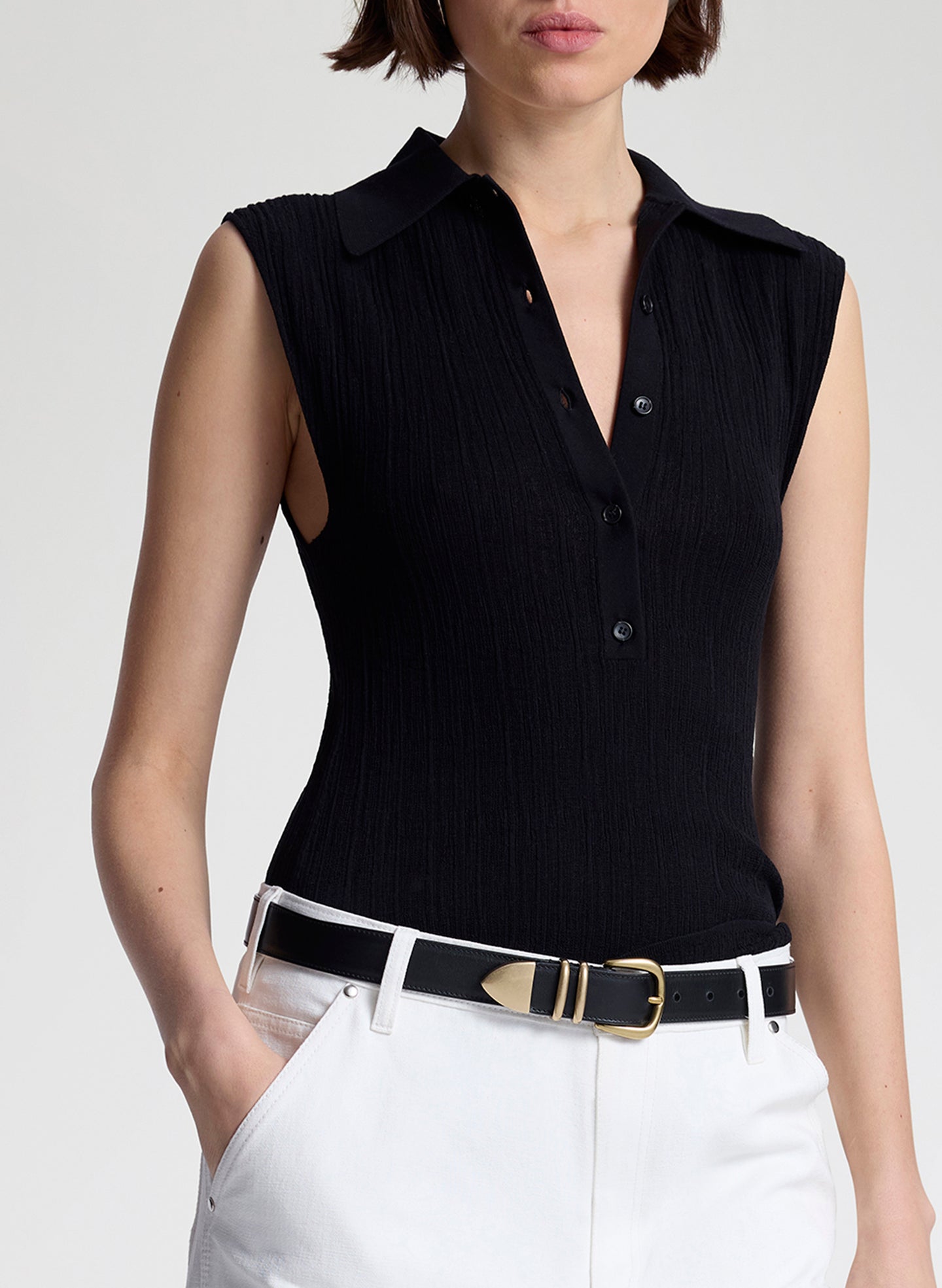 woman wearing  black sleeveless voile knit polo and white denim jeans