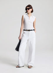 woman wearing  white sleeveless voile knit polo and white denim jeans