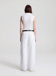 woman wearing  white sleeveless voile knit polo and white denim jeans