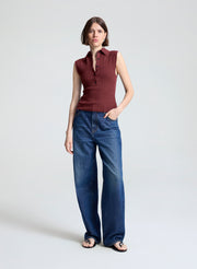 woman wearing burgundy sleeveless polo top and wide leg dark blue denim jeans