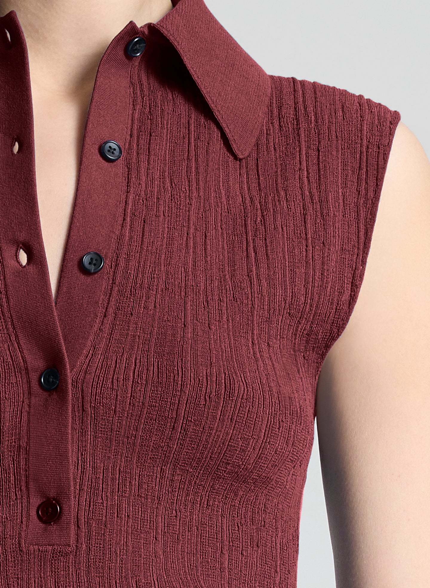 woman wearing burgundy sleeveless polo top and wide leg dark blue denim jeans