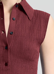 woman wearing burgundy sleeveless polo top and wide leg dark blue denim jeans