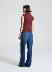 woman wearing burgundy sleeveless polo top and wide leg dark blue denim jeans