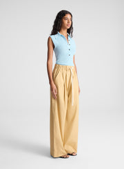 woman wearing ight blue sleeveless fine gauge knit polo top and beige wide leg pants