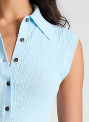 woman wearing ight blue sleeveless fine gauge knit polo top and beige wide leg pants