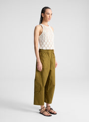 woman wearing cream knit tank and olive green wide leg pants