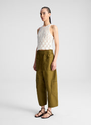 woman wearing cream knit tank and olive green wide leg pants