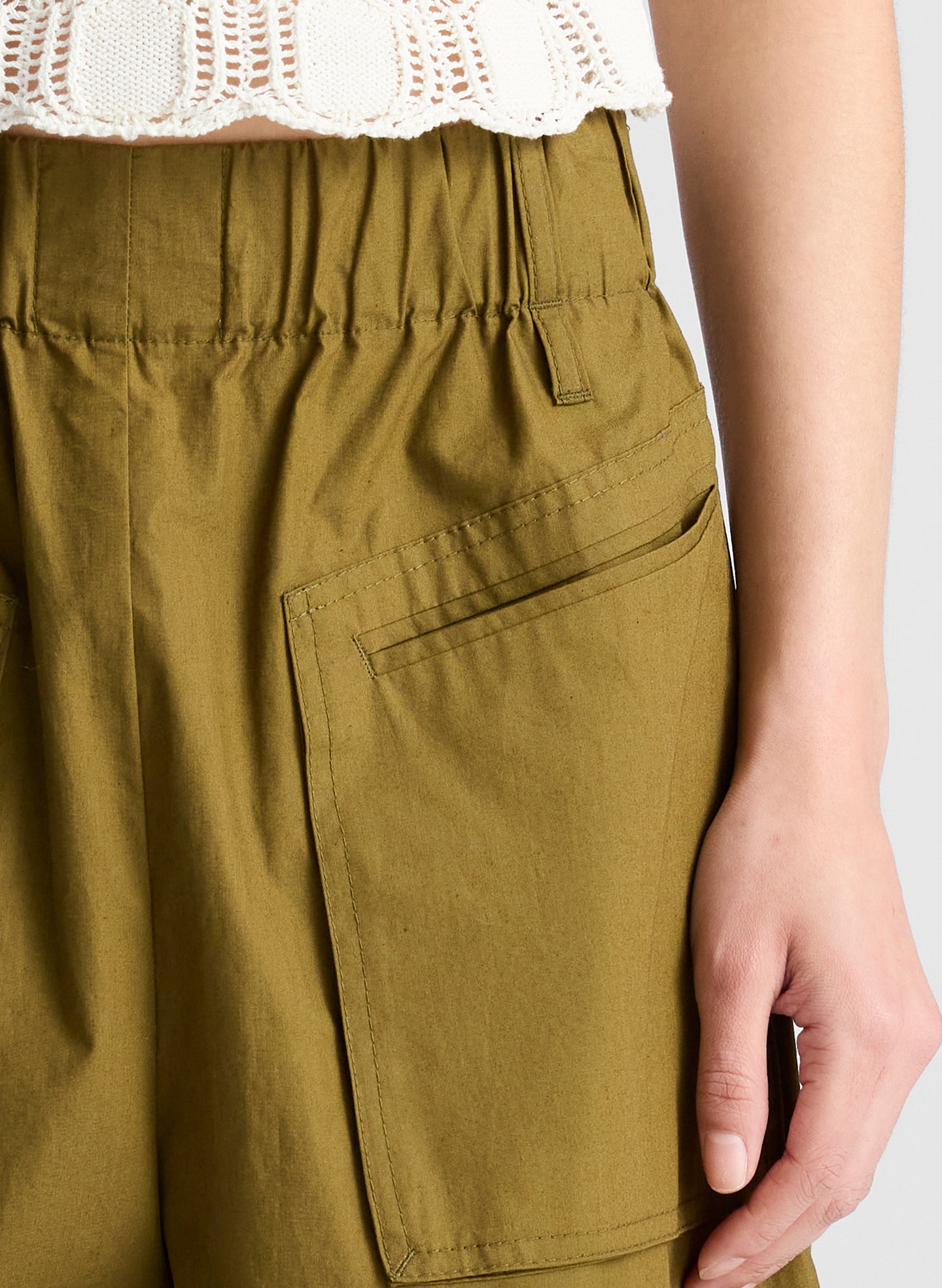 woman wearing cream knit tank and olive green wide leg pants