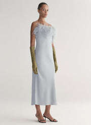 woman wearing blue father trimmed dress and green gloves