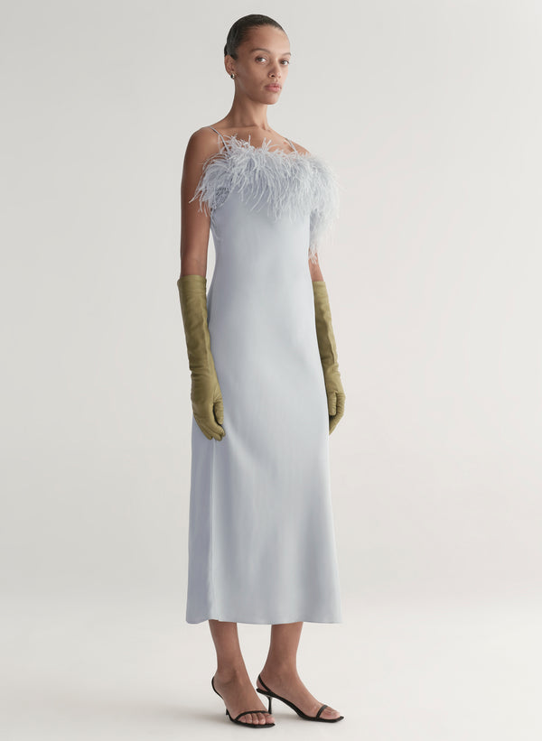 woman wearing blue father trimmed dress and green gloves