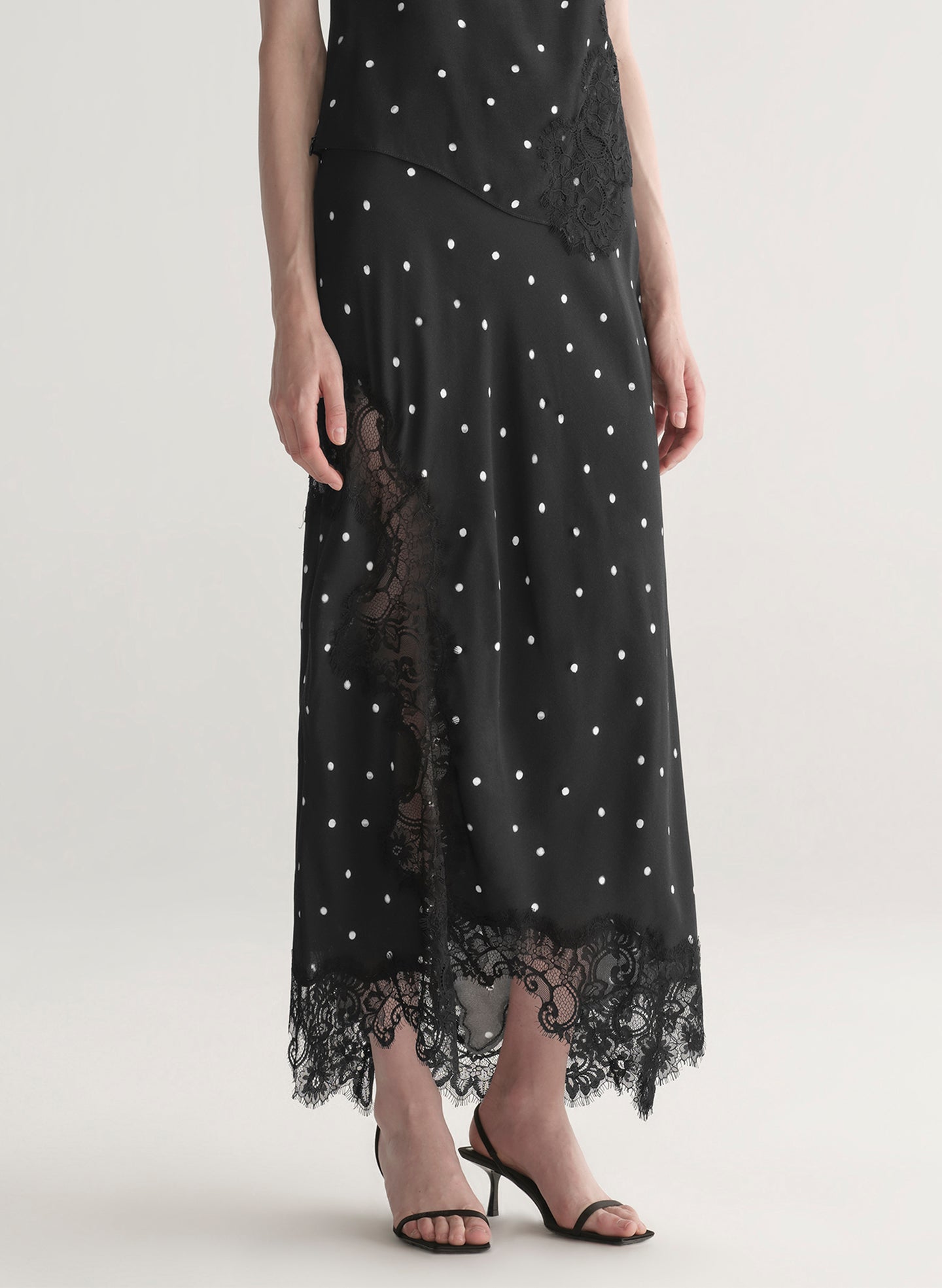 woman wearing black satin and lace polka dot top and matching midi skirt