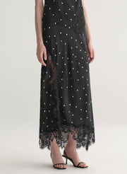 woman wearing black satin and lace polka dot top and matching midi skirt